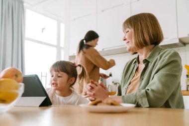 Beyaz kız ailesiyle evde vakit geçirirken tablet bilgisayar kullanıyor.