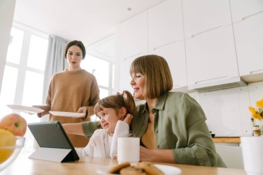 Beyaz kız ailesiyle evde vakit geçirirken tablet bilgisayar kullanıyor.