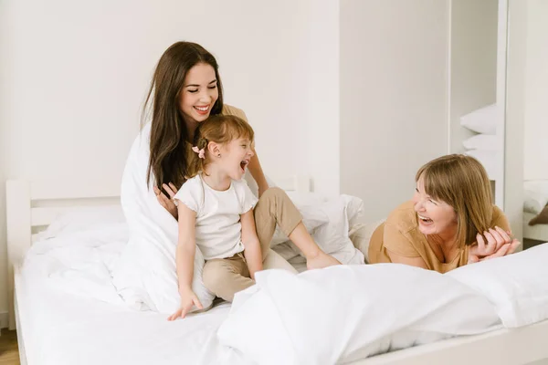 一个白人女孩在家里和她的母亲和孙女在床上玩耍 — 图库照片