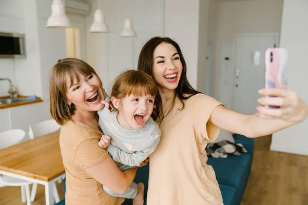 White family laughing while taking selfie photo on mobile phone at home