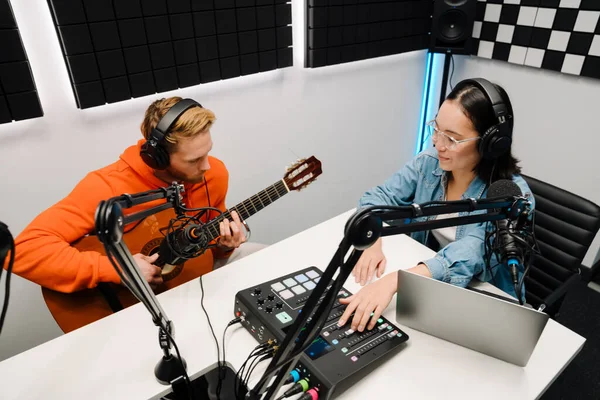 남자가 기타를 여자가 라디오 스튜디오에서 노트북으로 캐스트를 — 스톡 사진