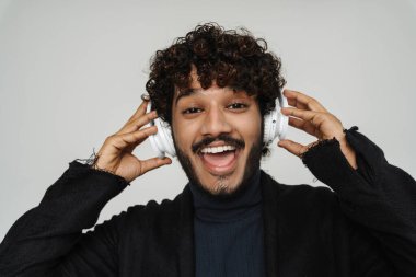 Gri arka planda, kulaklık takmış hevesli Hintli genç bir adamın portresi.