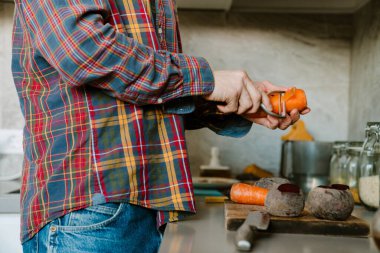 Beyaz adam gömleğini giyip evde yemek pişirirken sebze doğruyor.