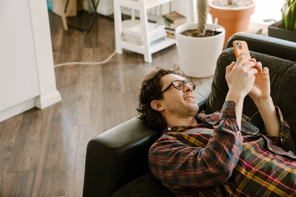 Hombre Blanco Sonriendo Usando Teléfono Móvil Mientras Descansa Sofá Casa — Foto de Stock