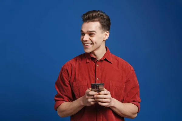 Mavi Arka Planda Gülümseyen Cep Telefonu Kullanan Genç Beyaz Bir — Stok fotoğraf