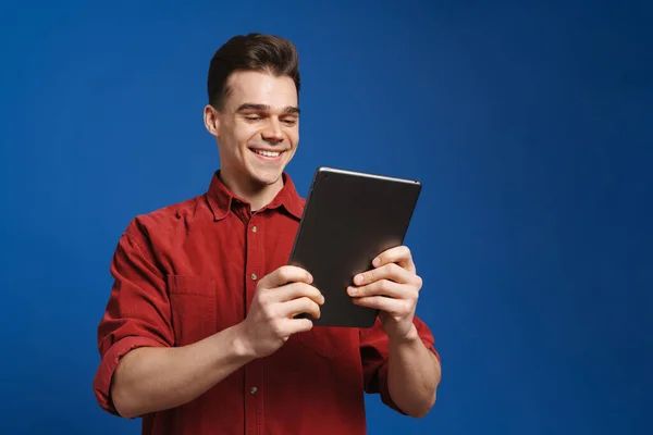 Mavi Arka Planda Gülümseyen Tablet Bilgisayar Kullanan Genç Beyaz Bir — Stok fotoğraf