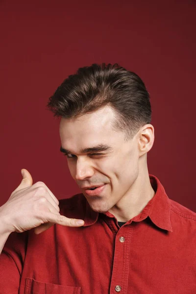 Jonge Blanke Man Maken Handset Gebaar Knipperen Geïsoleerd Rode Achtergrond — Stockfoto