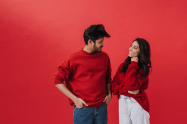 Genç Hintli çift kırmızı arka planda tek başına poz verirken gülüyor.