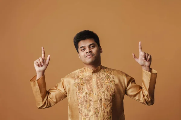 若いインド人男性笑顔と上の黄色の背景に隔離された指を指す — ストック写真
