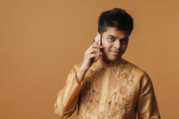 若いですブルネットインディアン男笑顔と話上の携帯電話隔離上の黄色の背景 — ストック写真