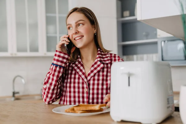 Young White Woman Wearing Pajama Eating Toasts Talking Cellphone Kitchen — Stock Photo, Image