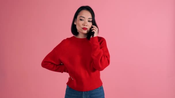 笑顔アジアの女性身に着けています赤いセーター見ますザ カメラでザピンクスタジオ — ストック動画