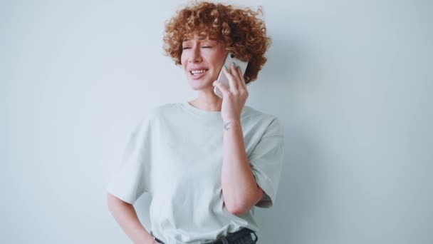 Θετική Γυναίκα Σγουρά Μαλλιά Μιλάει Στο Τηλέφωνο Στο Γκρίζο Στούντιο — Αρχείο Βίντεο