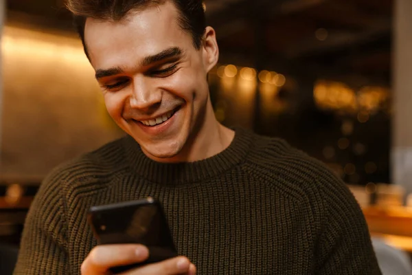 Kafede Cep Telefonu Kullanırken Gülümseyen Esmer Genç Bir Adam — Stok fotoğraf