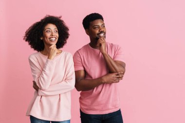 Siyahi mutlu adam ve kadın pembe arka planda izole edilmiş bir şekilde düşünüyor ve bakıyorlar.