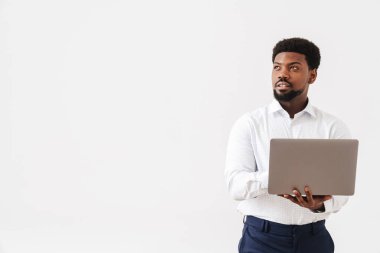 Siyah sakallı adam beyaz arka planda laptopla çalışıyor.