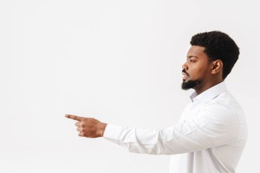Siyah, orta yaşlı, gömlekli, beyaz arka planda yalnız bir şekilde parmakla işaret eden bir adam.