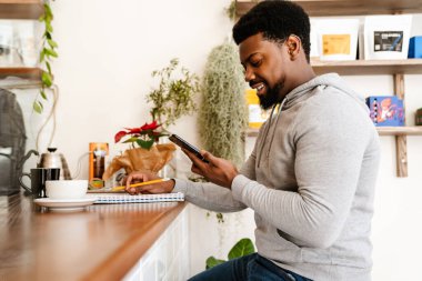 Kafede çalışırken cep telefonu kullanan siyah sakallı bir adam.