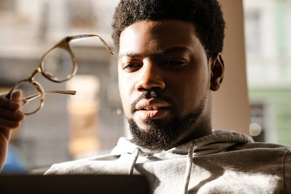 Černý Vousatý Muž Drží Brýle Při Práci Notebookem Kavárně — Stock fotografie