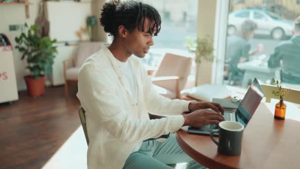 Leende Afrikansk Man Arbetar Laptop Nära Fönstret Caféet — Stockvideo
