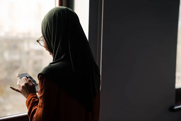 Backview Jeune Femme Hijab Lunettes Regardant Son Téléphone Devant Fenêtre — Photo