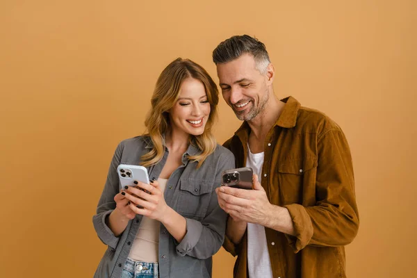 White Happy Couple Using Mobile Phones While Laughing Isolated Beige — Stock Photo, Image