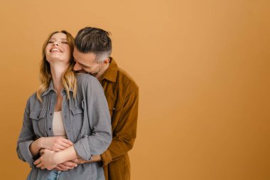 Beyaz mutlu çift bej arka planda gülüyor ve sarılıyorlar.