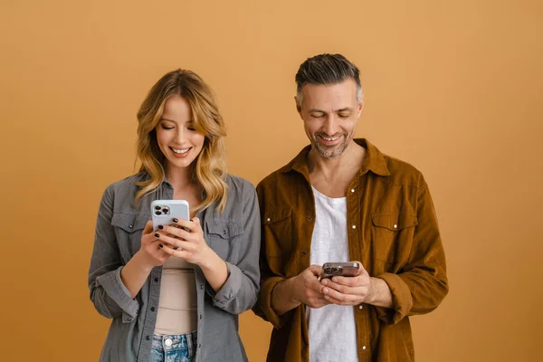 Weißes Glückliches Paar Benutzt Mobiltelefone Während Isoliert Über Beigen Hintergrund — Stockfoto
