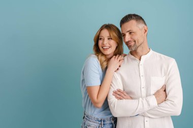 Beyaz mutlu çift sarılıyor ve gülümsüyor. Mavi arka planda tek başlarına.