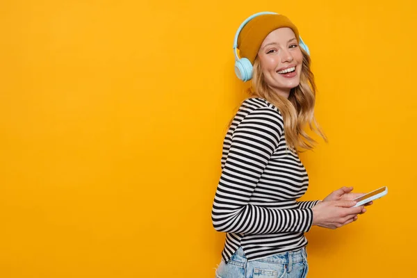 Young Blonde Woman Using Cellphone While Listening Music Isolated Yellow — Stock Photo, Image