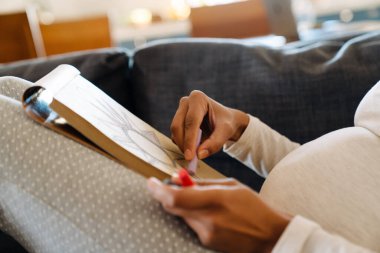 Hands of pregnant african woman drawing flower in a sketchbook close-up