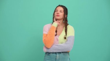 Pensive young woman with pigtails thinking about something in the turquoise studio
