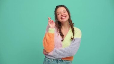 Cheerful young woman with pigtails hoping for something in the turquoise studio