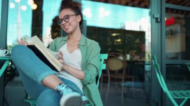 Cafe 'de gözlük takıp kitap okuyan sevimli Afrikalı kadın.