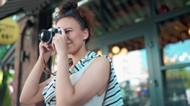 Güzel Afrikalı turist kadın dışarıda kamerayla caddenin fotoğraflarını çekiyor.