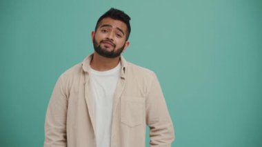 Sıkıcı Orta Doğulu genç adam turkuaz stüdyoda el sıkışıyor.