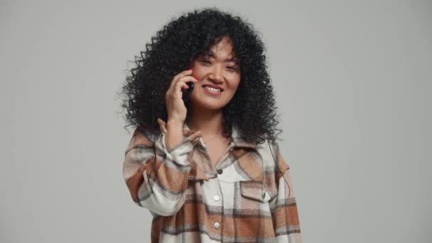 Happy Brunette Asian Woman Talking Mobile Grey Studio — Vídeo de Stock