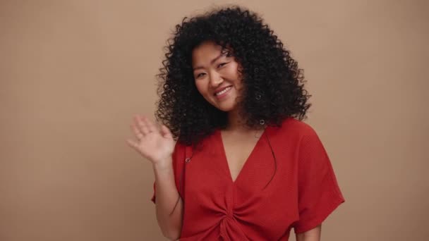 Щаслива Жінка Брюнетки Азіатка Махає Рукою Камеру Бежевій Студії — стокове відео