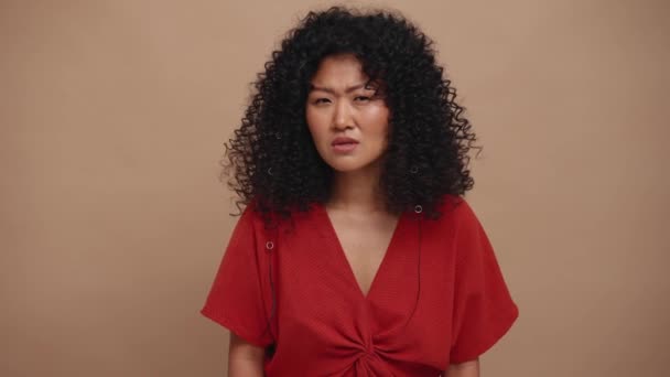Displeased Curly Haired Asian Woman Peering Camera Beige Studio — Video