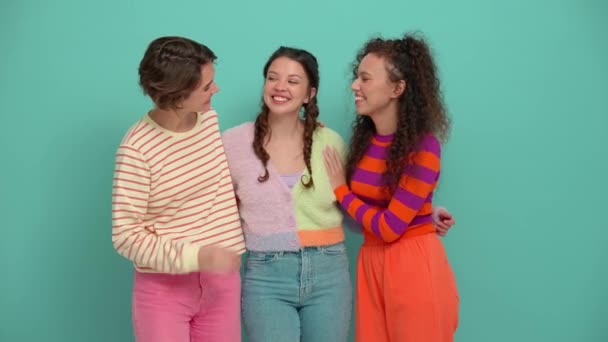 Три Щасливі Молоді Дівчата Обіймаються Дивляться Один Одного Бірюзовій Студії — стокове відео