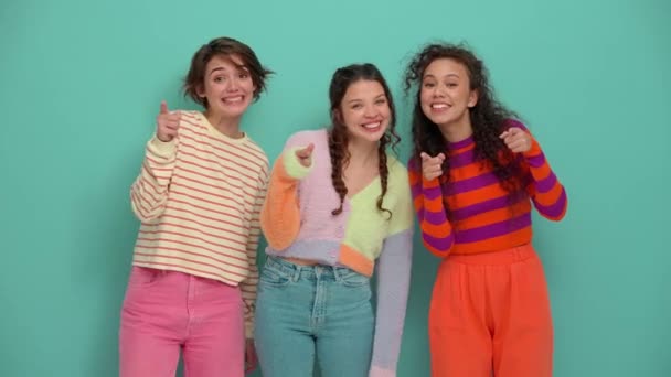 Три Веселих Молодих Дівчат Вказують Пальці Камеру Вниз Бірюзовій Студії — стокове відео