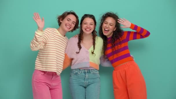 Три Прекрасні Молоді Дівчата Махають Рукою Камери Бірюзовій Студії — стокове відео