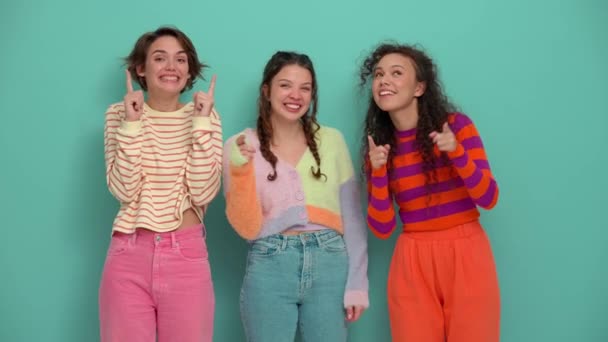 Three Smiling Young Girls Pointing Fingers Camera Turquoise Studio — Vídeo de stock