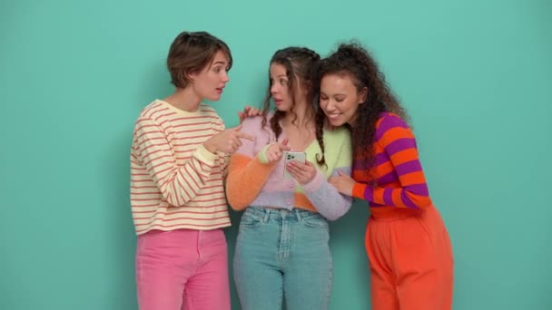 3人の幸せな若い女の子がトルコ石のスタジオでモバイルで何かを話し合う — ストック動画