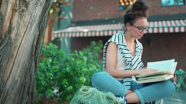 Smiling African Woman Wearing Eyeglasses Reading Book Bench Outdoors — Vídeo de stock