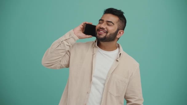 Positive Middle Eastern Young Man Talking Mobile Gesturing Turquoise Studio — Vídeo de stock