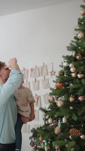 Серьезный Блондин Отец Дочь Смотрят Игрушки Рождественской Елке Дома — стоковое видео