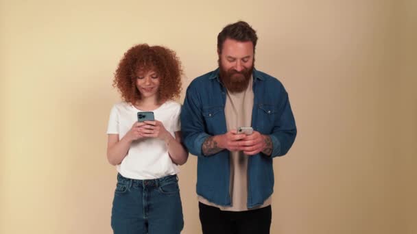 米色工作室里穿着休闲装 头戴红头发的夫妇在手机上打字 — 图库视频影像