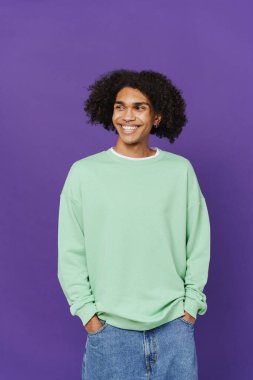 Young caribbean man with piercing smiling and looking aside isolated over purple background