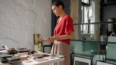Pretty brunette woman architect working on tablet near samples on a table in the office